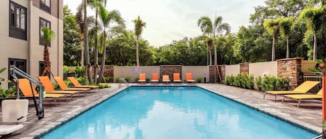 Una piscina con sillas de descanso y palmeras.