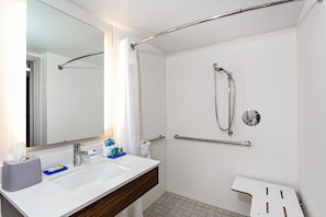 Un baño moderno con un lavamanos, espejo y ducha blancos.