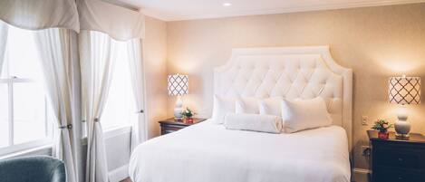 A neatly arranged hotel room with a large bed, two bedside tables, a chair, and a window with curtains.