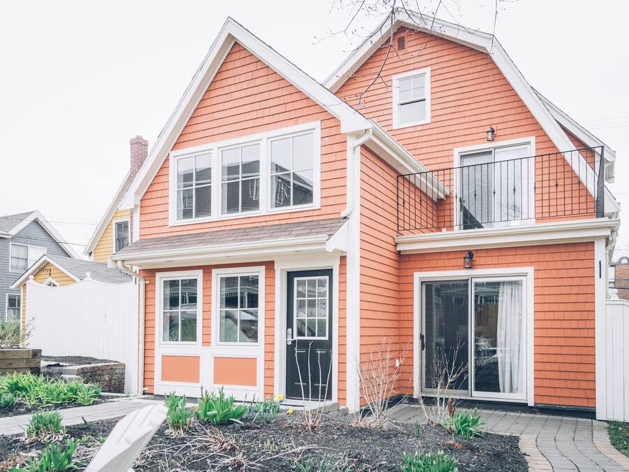 A two-story house with a red exterior, white trim, and a front porch.