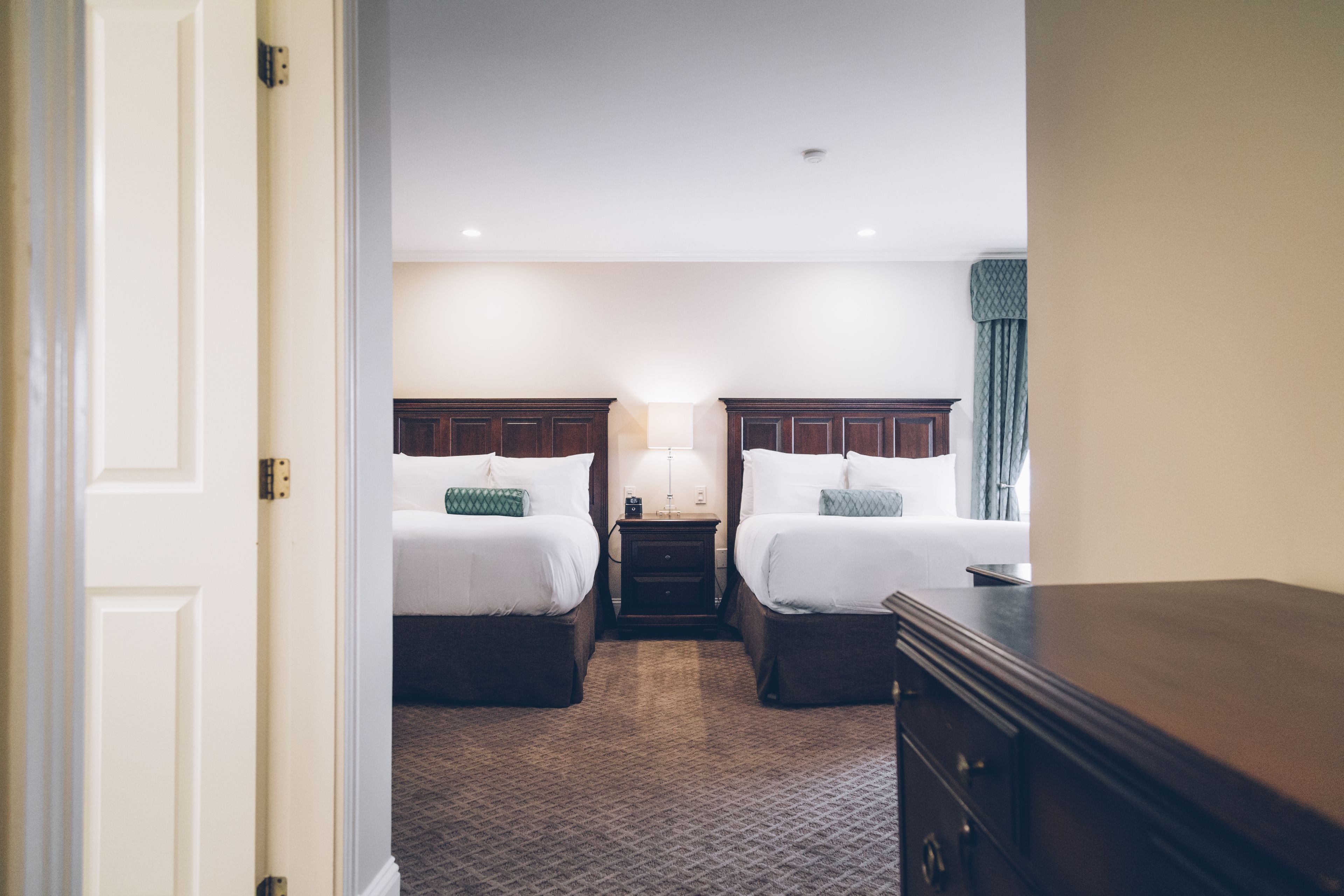 Quarto de hotel com duas camas, uma mesa de cabeceira e um armário.
