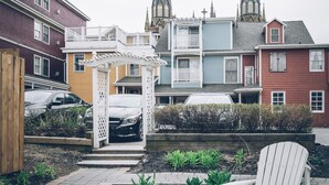 Zona residencial con una iglesia que presenta dos torres, una terraza de madera y una silla blanca en primer plano.