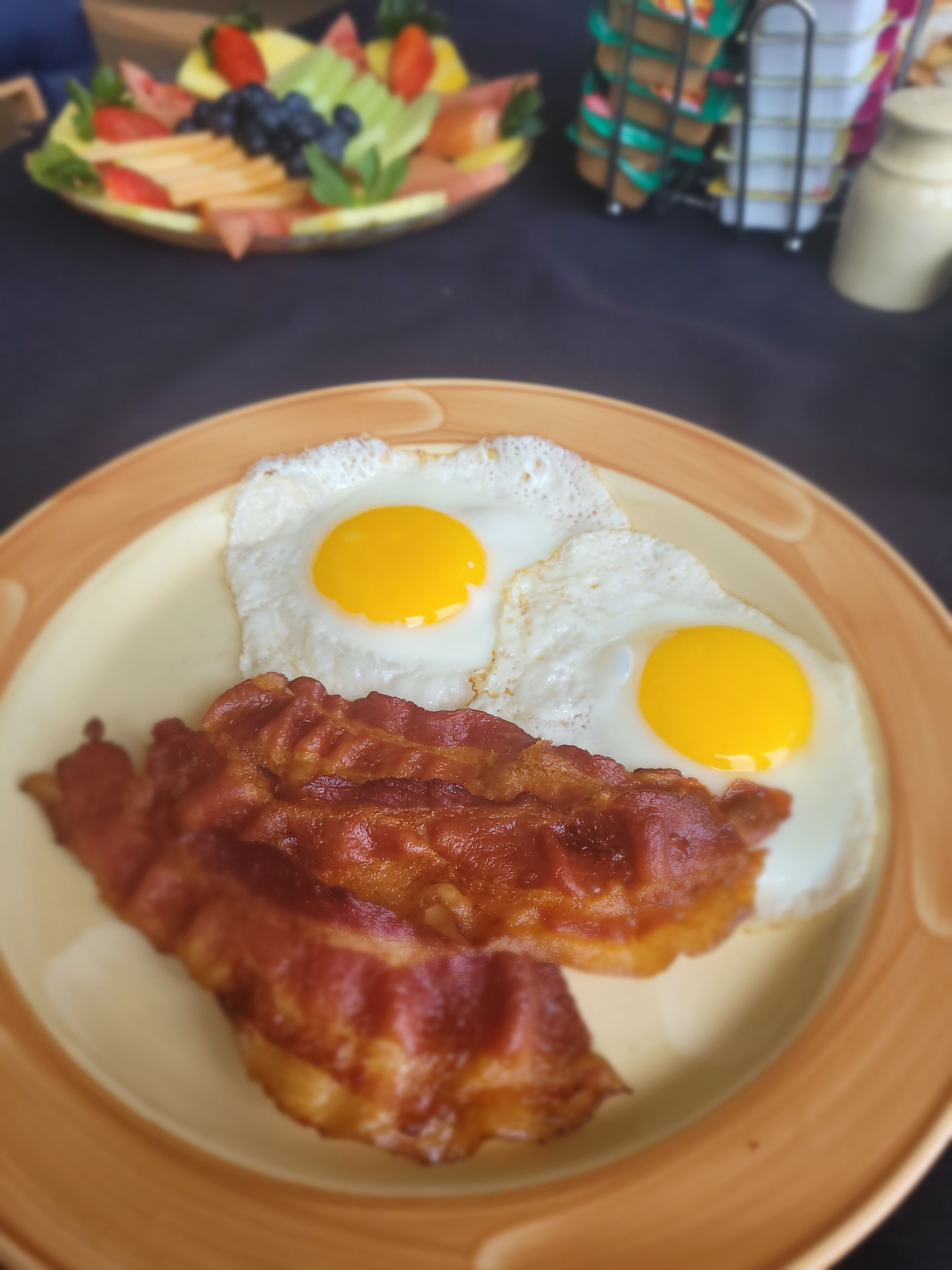 A plate with two fried eggs and a slice of bacon.