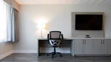 Una habitación de hotel con escritorio, silla, televisor y lámpara.