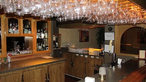 A bar area with wooden cabinets, a granite countertop, and a variety of glassware and bottles.