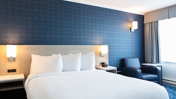 Una camera d'albergo con un letto grande, comodini, una scrivania, una sedia e una lampada.