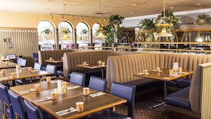 A restaurant interior with booths, tables, and blue chairs.