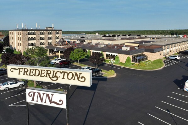 A hotel named 'Frederiston Inn' with a parking lot, a building with multiple floors, and a clear sky.