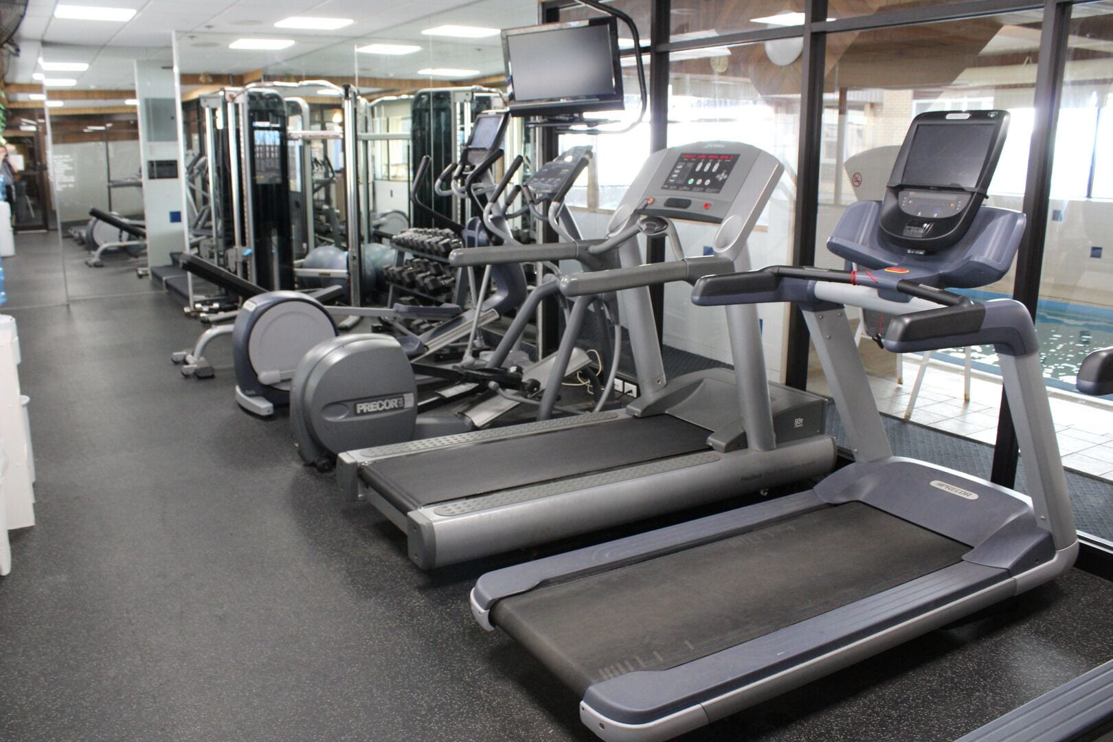 Un gimnasio con cintas de correr, elípticas y máquinas de pesas.
