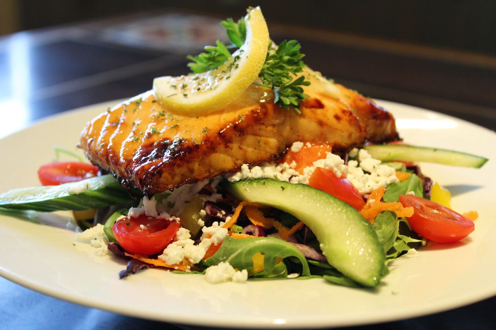 A plate with grilled chicken, salad, and lemon garnish.