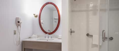 Baño con lavamanos, espejo, secador de pelo y ducha.