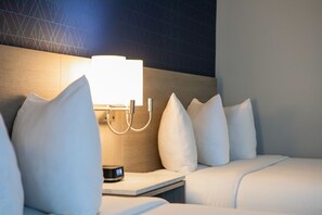 Une chambre d’hôtel avec un lit, une table de chevet avec une lampe et un mur orné de motifs géométriques.