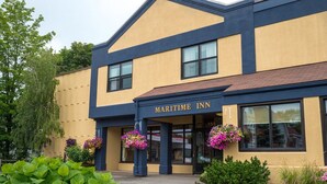 Un edificio de dos pisos con fachada amarilla y detalles en azul oscuro, identificado como "MARITIME INN".