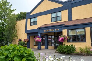 Un edificio de dos pisos con fachada amarilla y detalles en azul oscuro, identificado como "MARITIME INN".