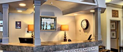A reception area with a marble counter, a clock, and framed pictures on the wall.