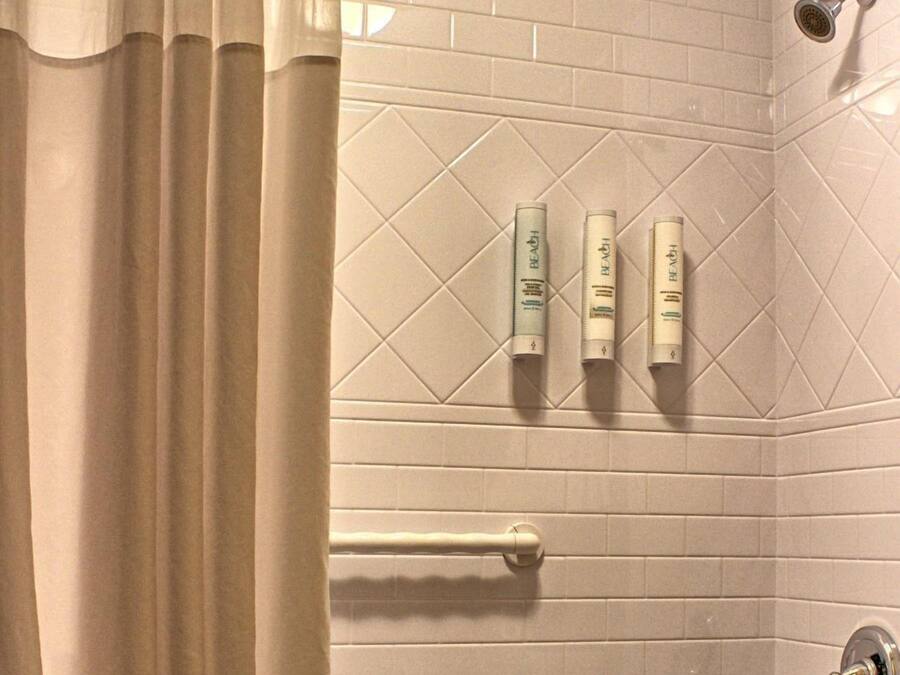 Een badkamer met een bad, een douchekop en drie toiletartikelen op de muur.