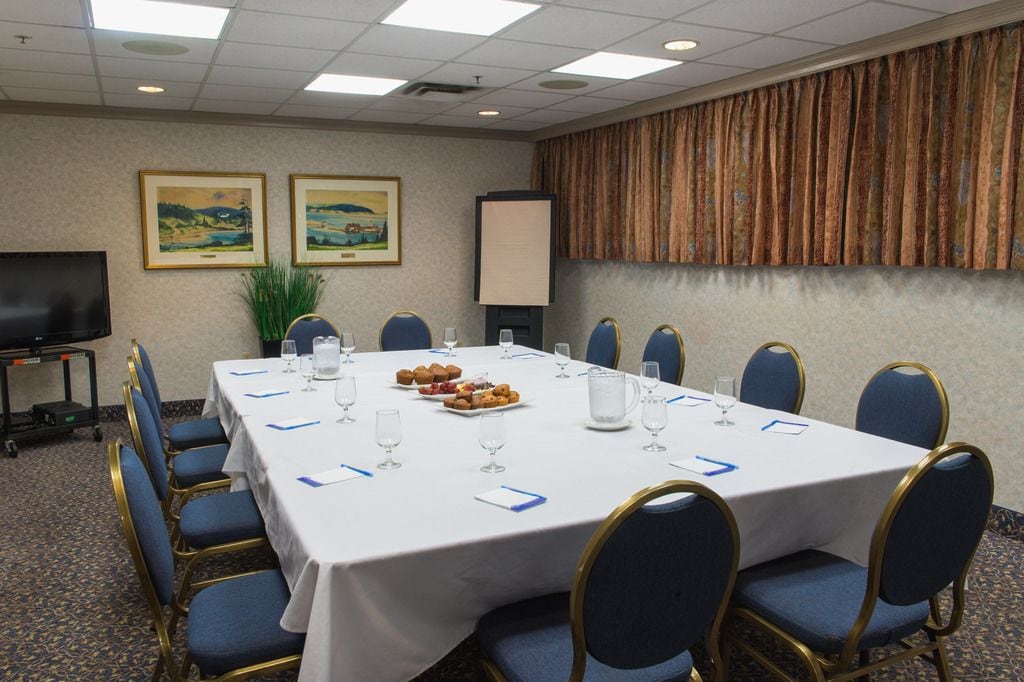 Un salón de conferencias con una larga mesa, sillas azules y una pantalla de proyector.