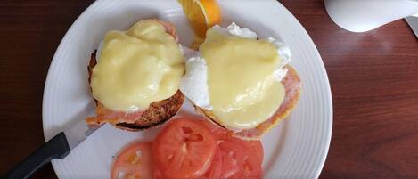 A plate with two open-faced sandwiches topped with egg yolk, a slice of tomato, and a slice of orange.