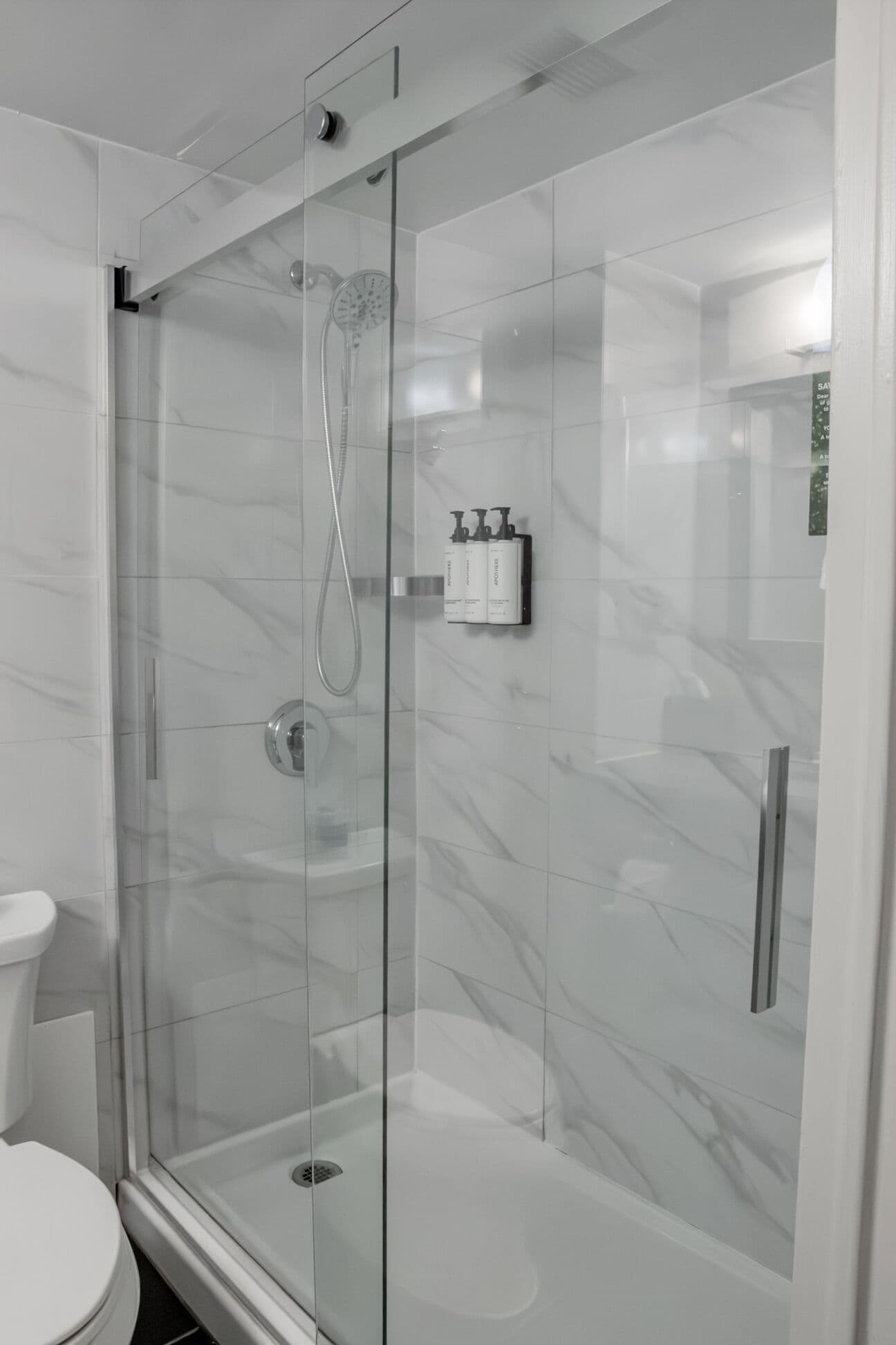 A modern bathroom with a glass-enclosed shower, a white toilet, and a marble backsplash.