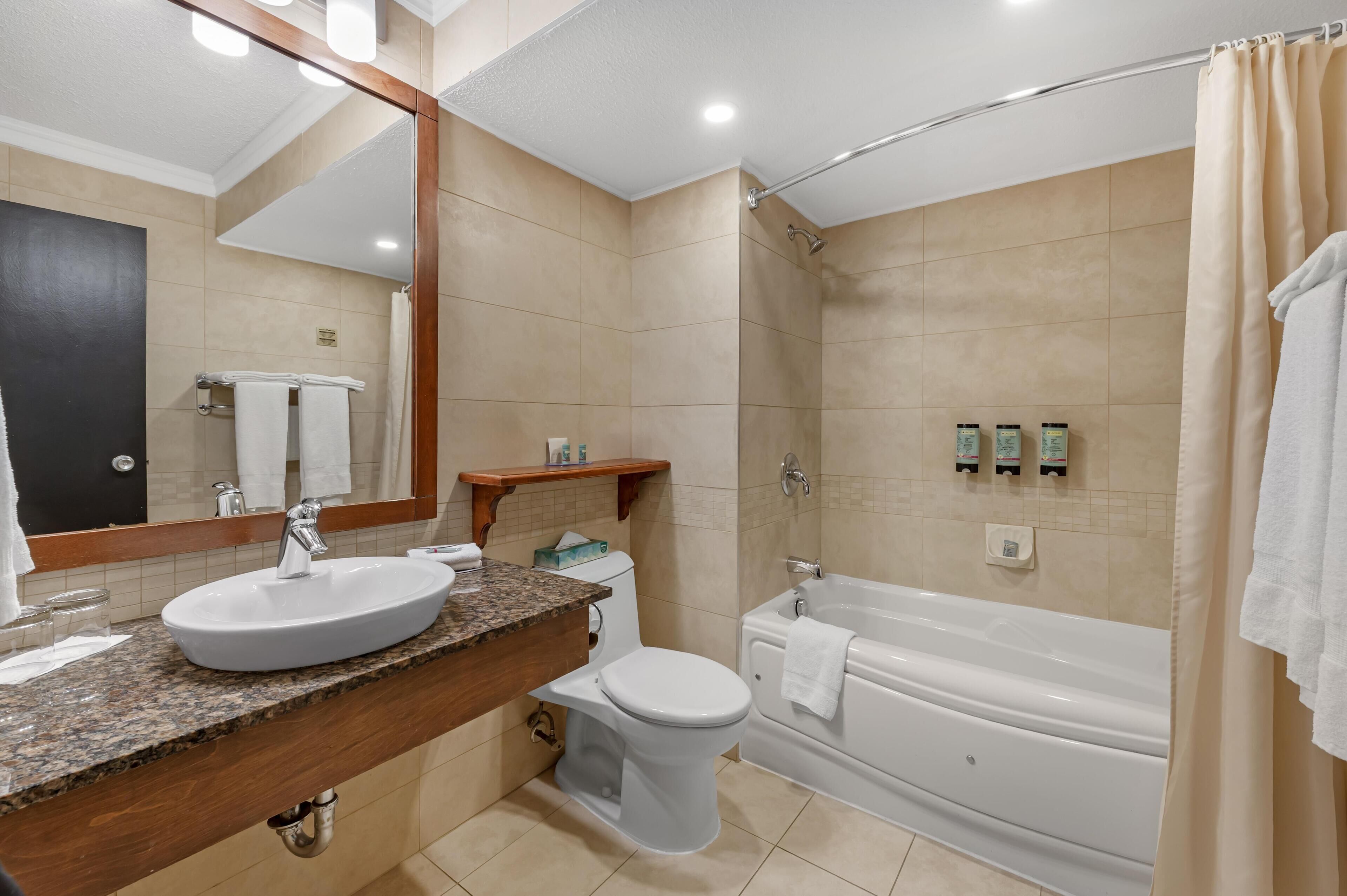 A modern bathroom with a sink, toilet, and bathtub.
