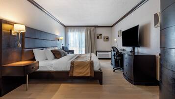 A modern hotel room with a large bed, bedside lamps, a flat-screen TV, a desk, and a wardrobe.