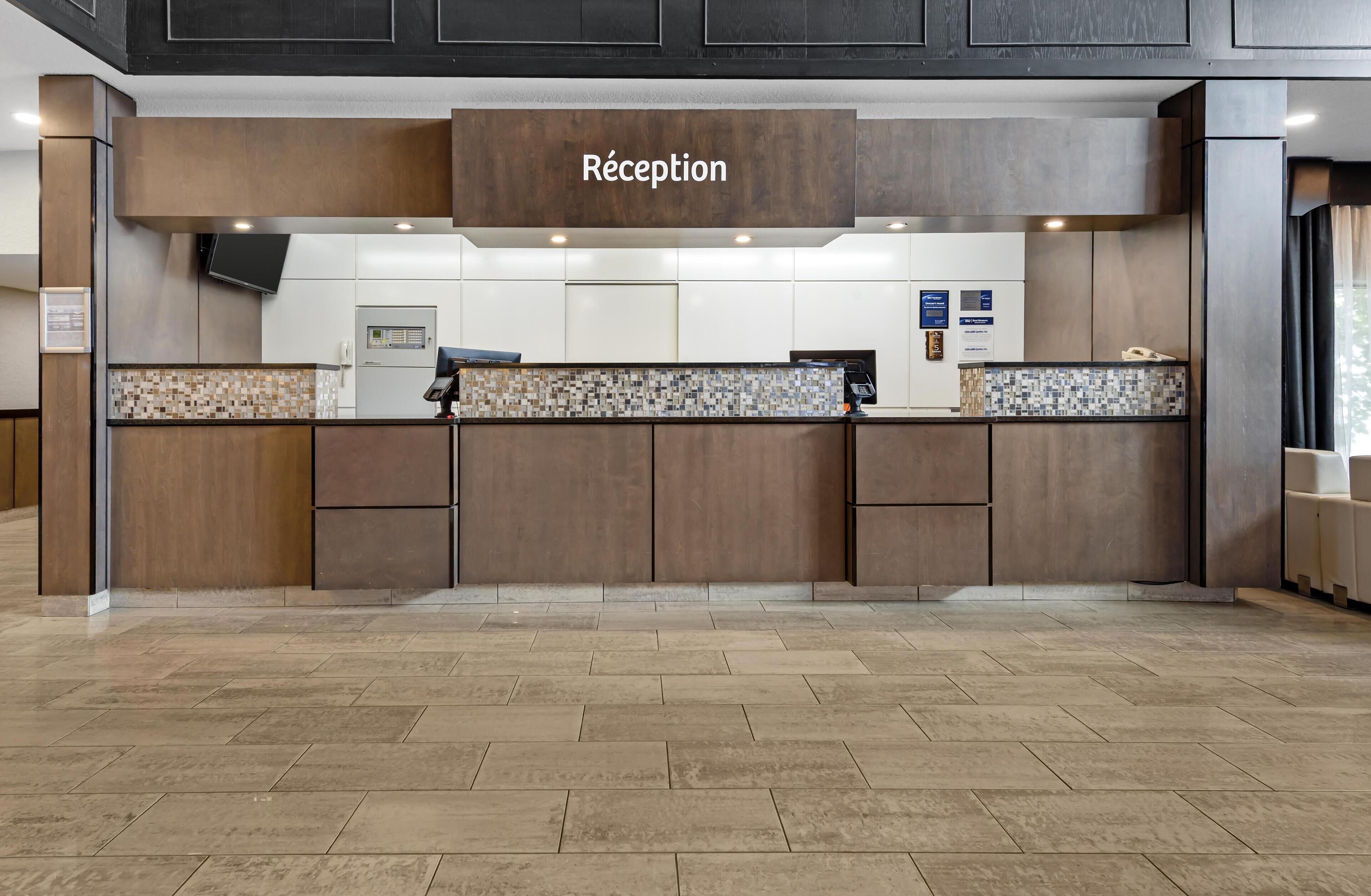 Un área de recepción con un letrero que dice 'Réception', un salpicadero de azulejos y un televisor de pantalla plana.