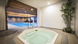 Un área de spa con una bañera de hidromasaje, una pared de piedra y una planta de bambú.