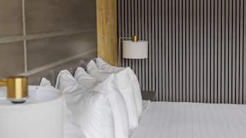 Una habitació d'hotel amb un llit gran, una làmpada de nit i una paret amb ratlles verticals.