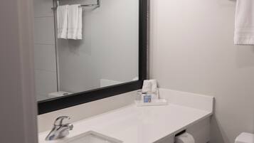 A modern bathroom with a white sink, a large mirror, and a toilet.
