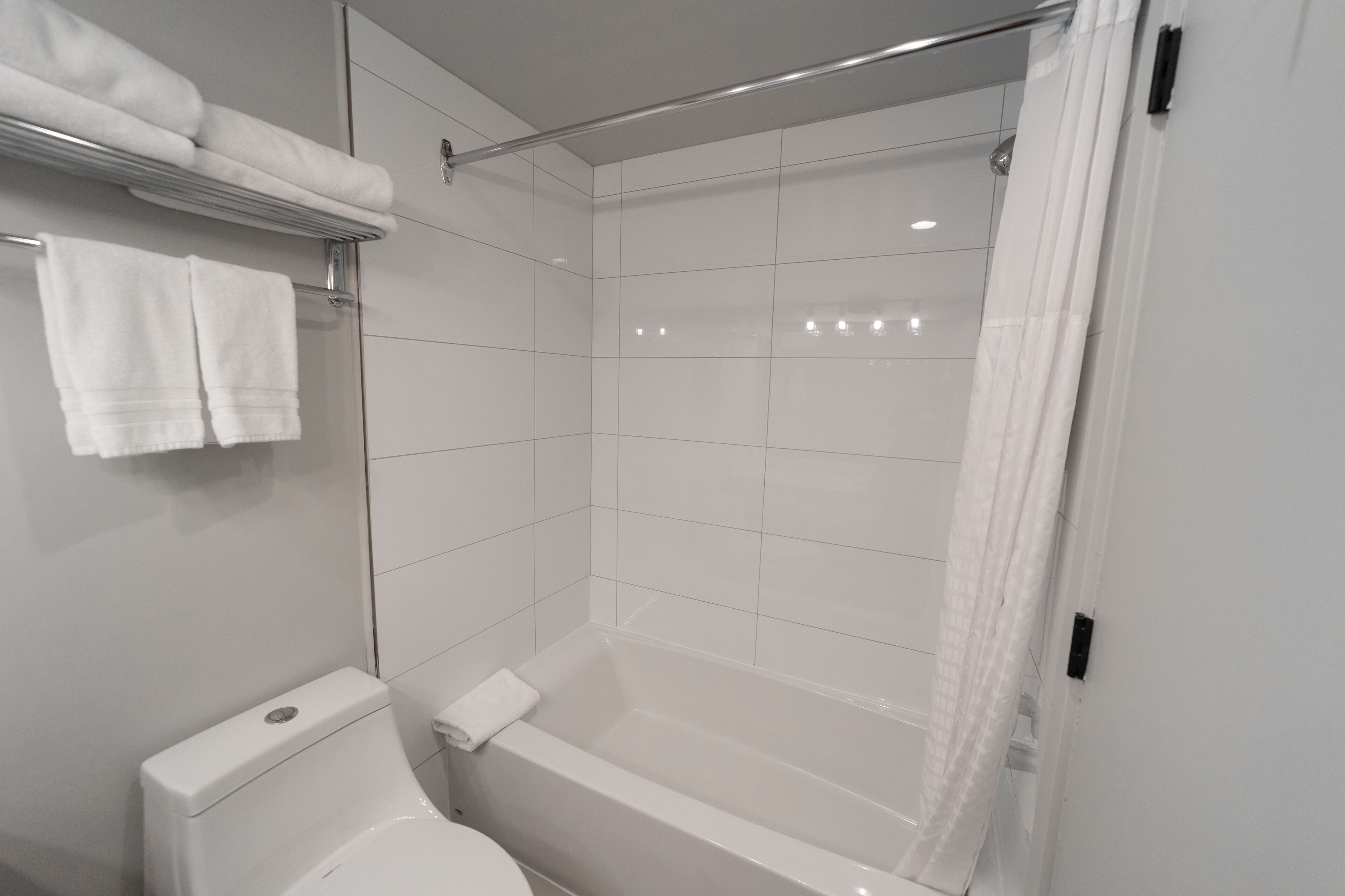 A modern bathroom with a toilet, bathtub, and shower curtain.