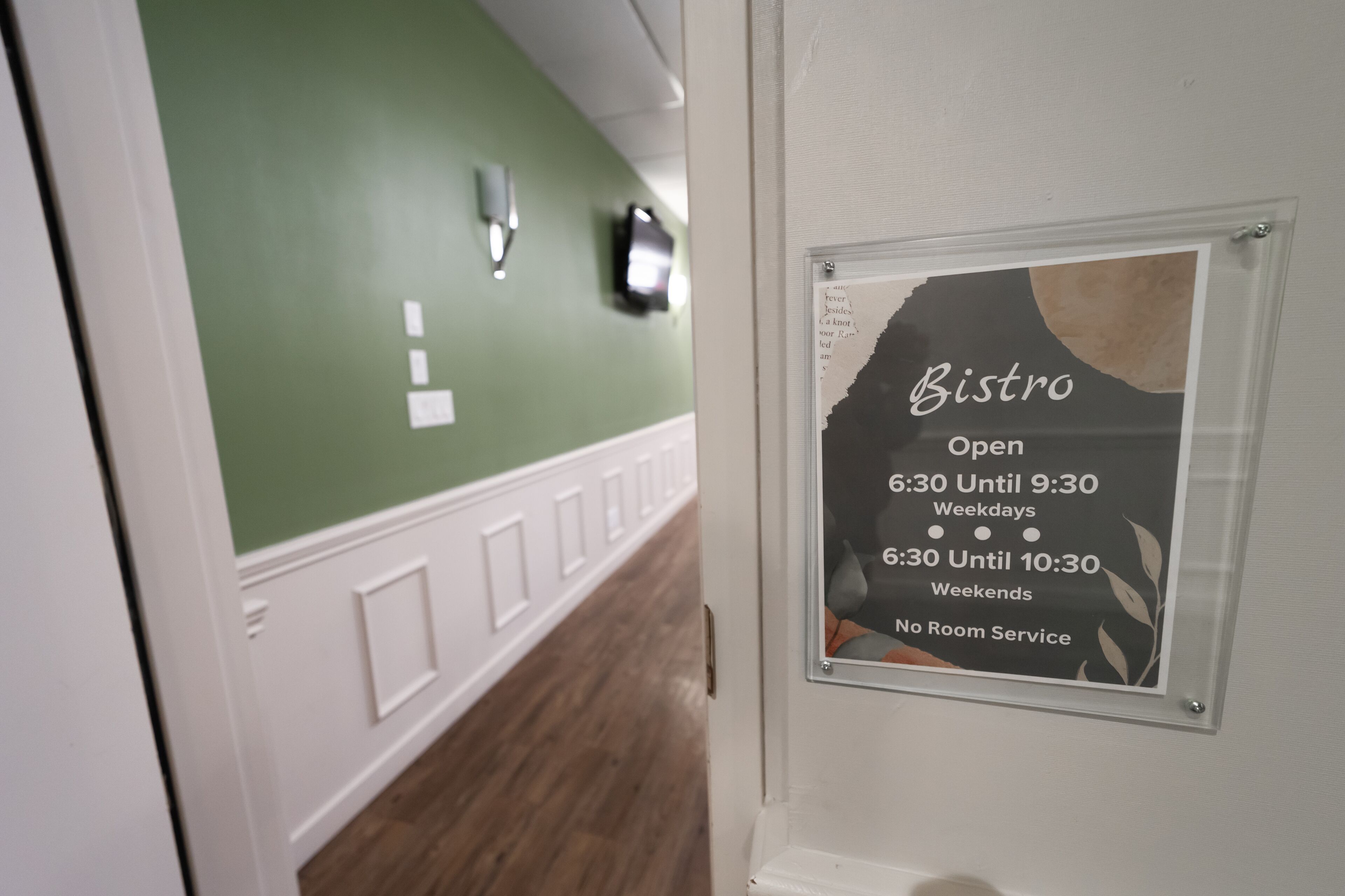 A hallway with a green wall and a sign indicating the Bistro's operating hours.
