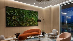 A modern living room with a large green wall art, a plush orange sofa, and a round coffee table.