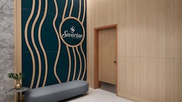 A modern room with a teal accent wall, a bench, a small table with a plant, and a wooden door.