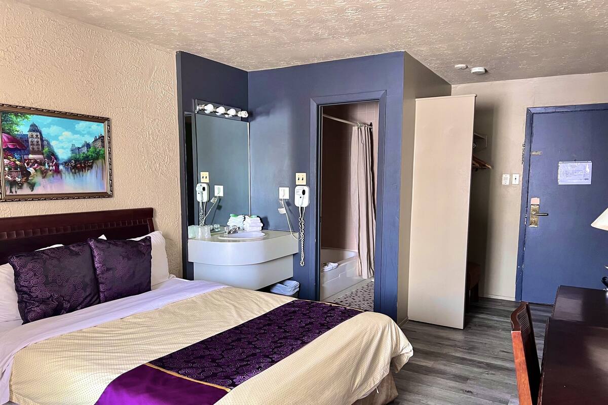 A hotel room with a bed, a bathroom, and a door leading to another room.
