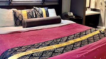 Ein Hotelzimmer mit einem großen Bett, einem Nachttisch, einem Spiegel und einem an der Wand befestigten Fernseher.