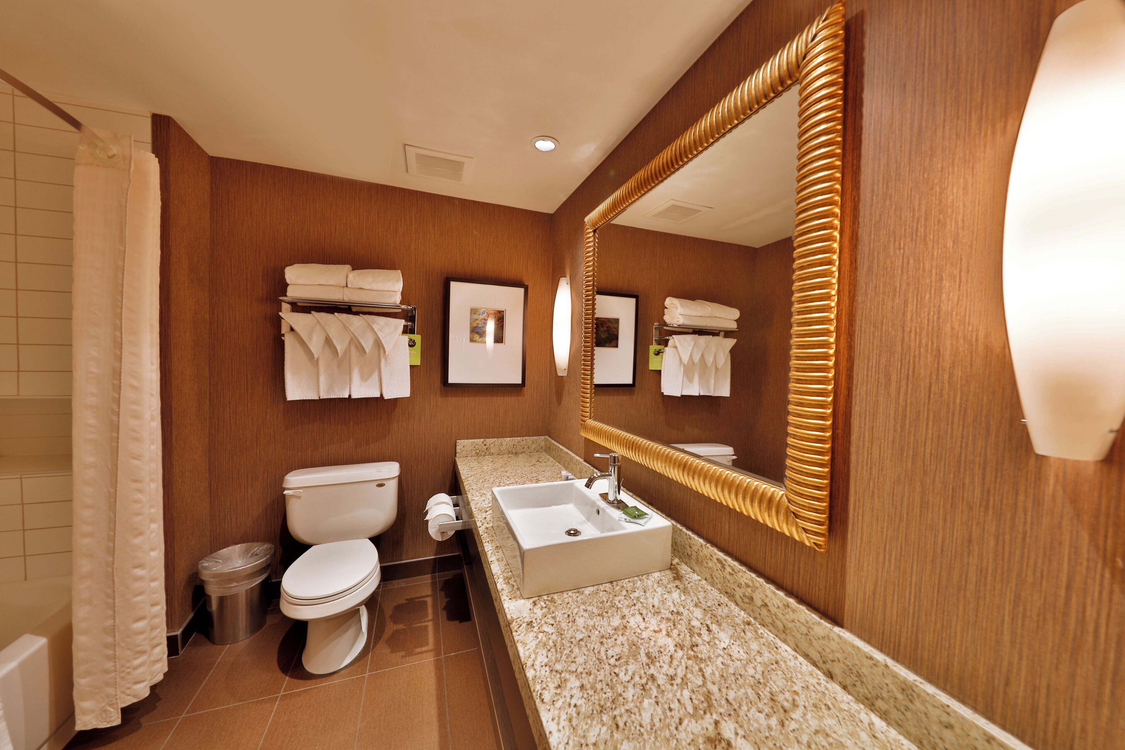 A modern bathroom with a wooden vanity, a large mirror, and a toilet.