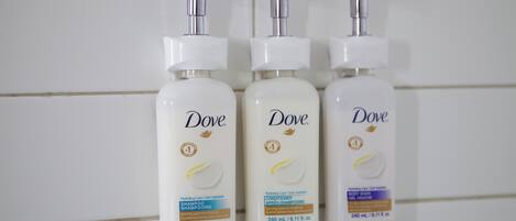 Three Dove skincare bottles against a tiled wall.