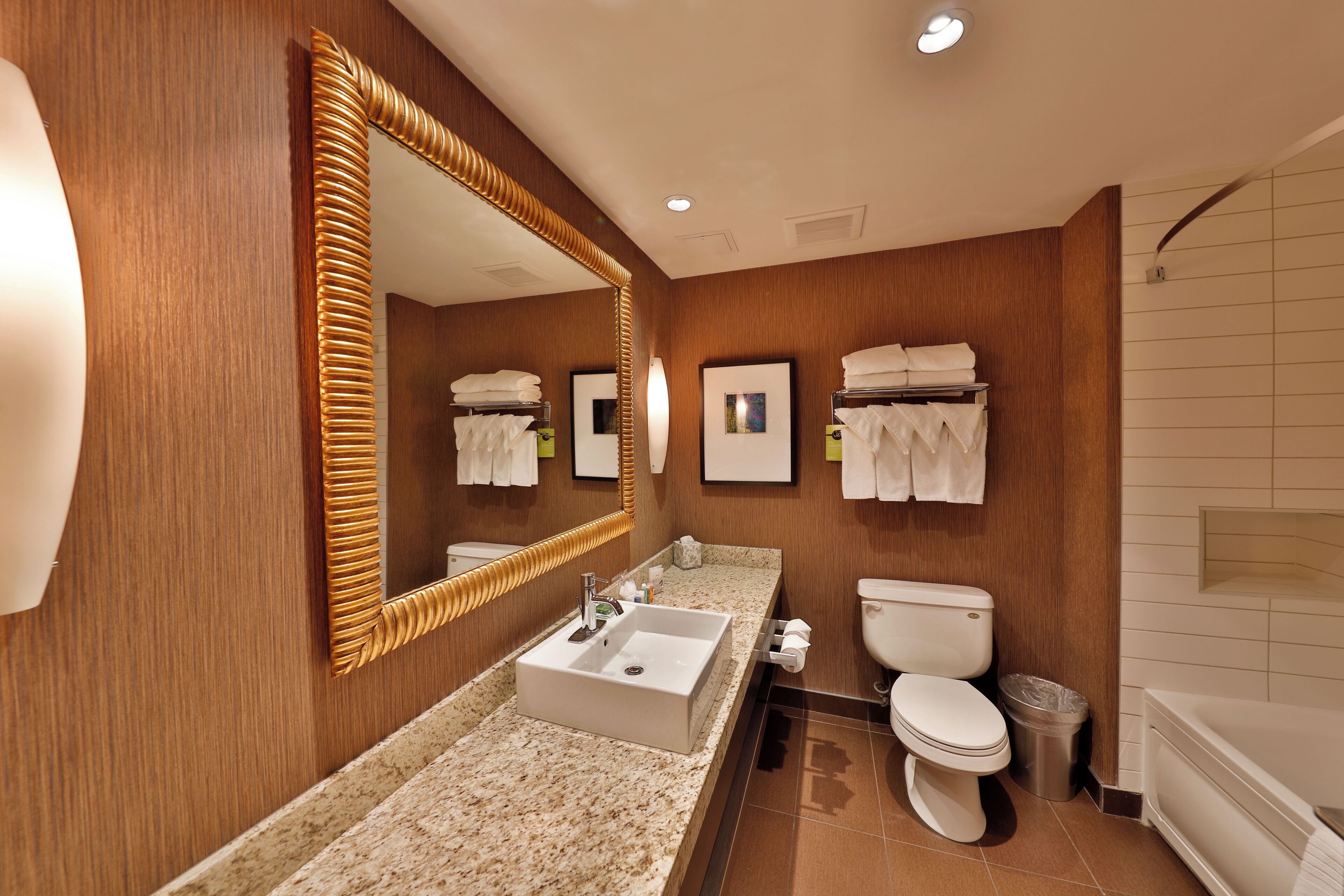 Un baño moderno con un espejo grande, un lavabo, un inodoro y una bañera.