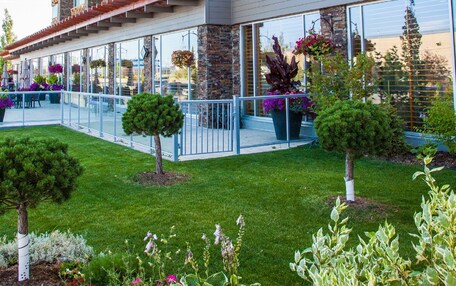 A multi-story hotel with balconies, large windows, and a well-maintained garden.