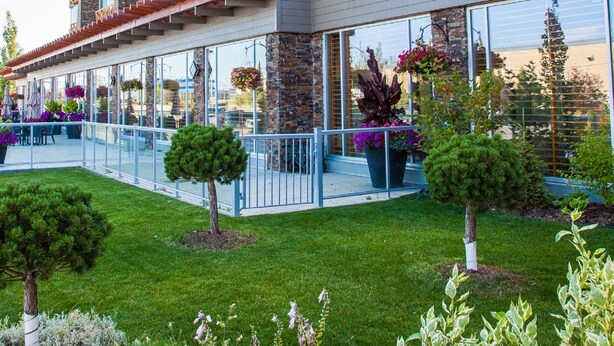 Un hotel de varios pisos con balcones, ventanas amplias y un jardín bien cuidado.