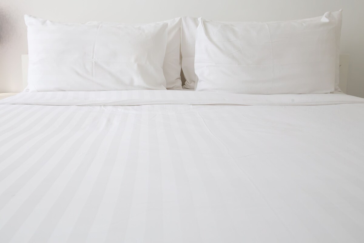 A bed with white bedding and pillows.