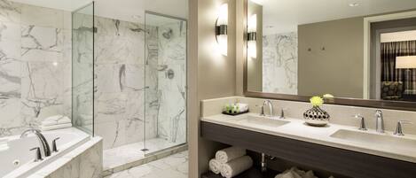A modern bathroom with a glass-enclosed shower, a large mirror, and a vanity with multiple sinks and towel storage.