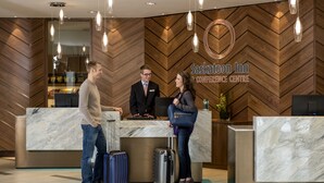 Zona de recepción con pared de madera en espiga, mostrador de recepción y logotipo del Saskatoon Inn Conference Centre.