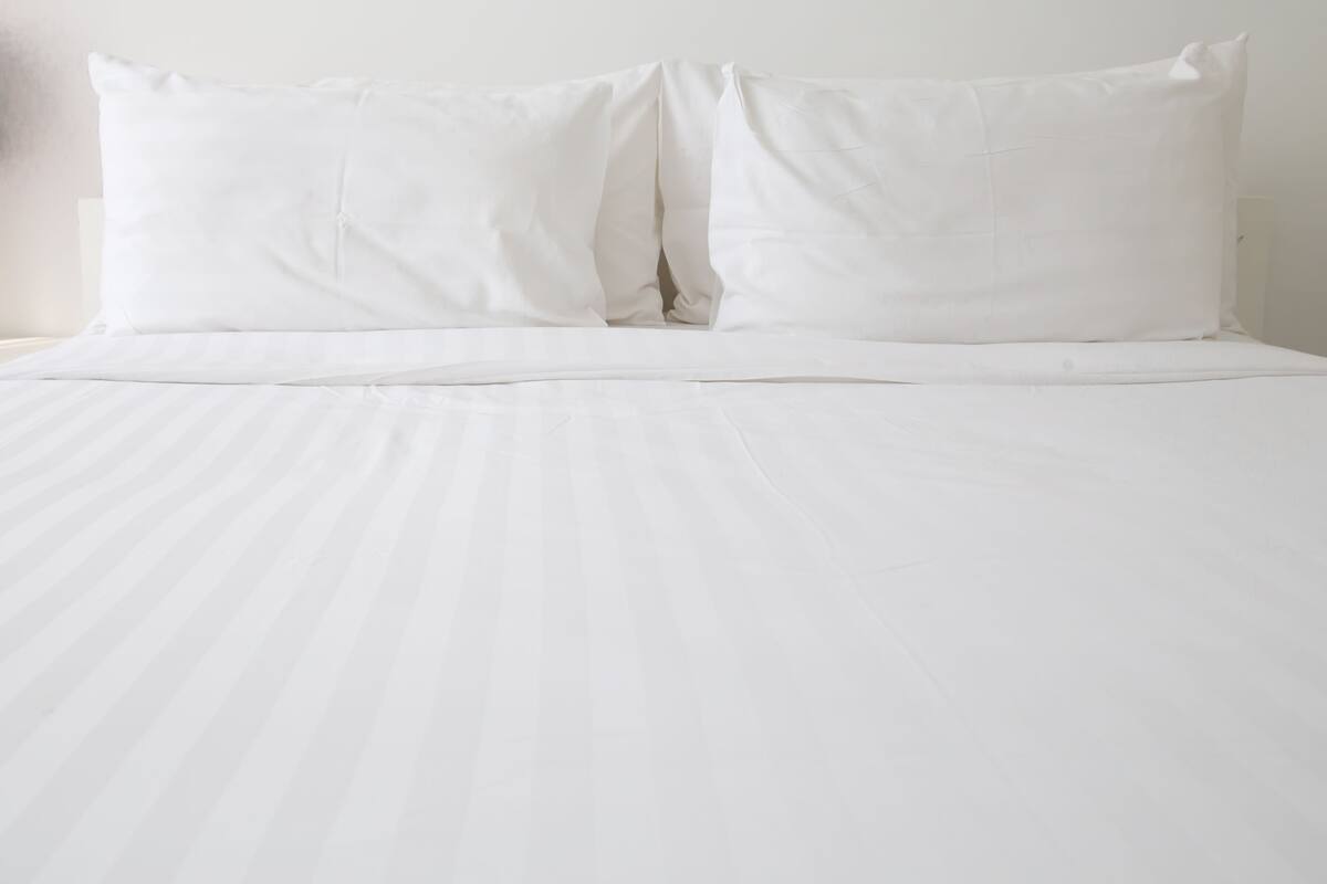 A bed with white bedding and pillows.