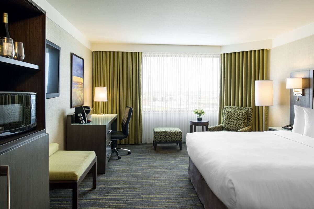 A hotel room with a bed, desk, chair, and a television.