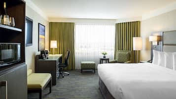 Habitación de hotel con cama, escritorio, silla y televisor.