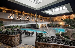 Ein Poolbereich im Innenbereich mit mehreren Ebenen, Steinwänden, Sitzgelegenheiten und einem zentralen Pool.