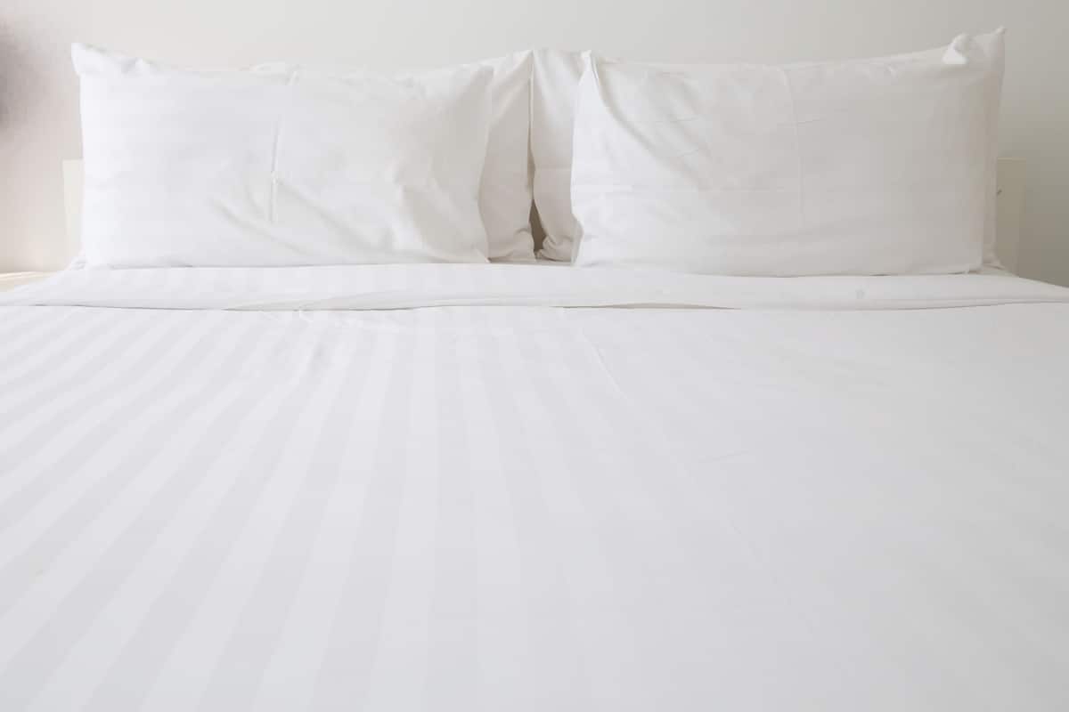 A bed with white bedding and pillows.