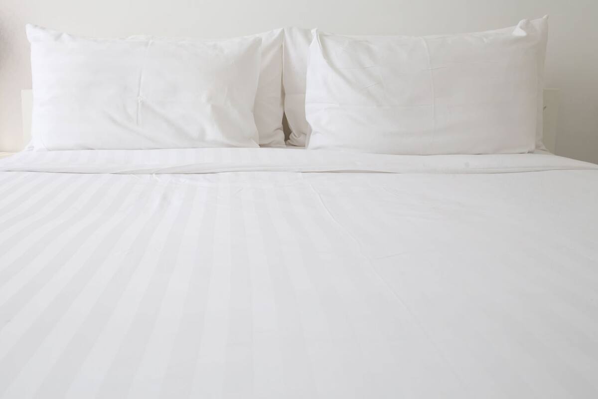 A bed with white bedding and pillows.