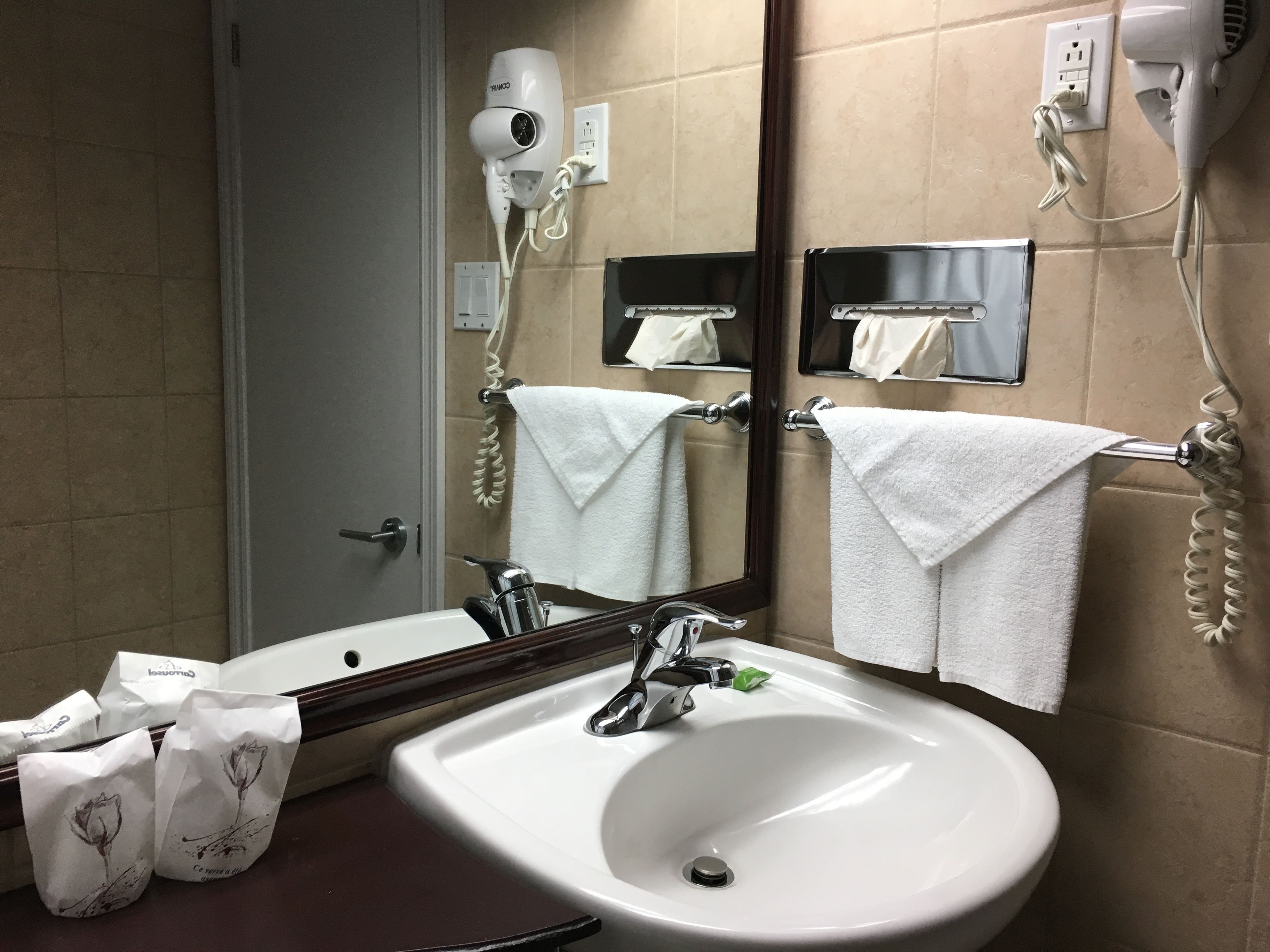 Un baño con lavamanos, espejo, toallero, secador de pelo y teléfono.